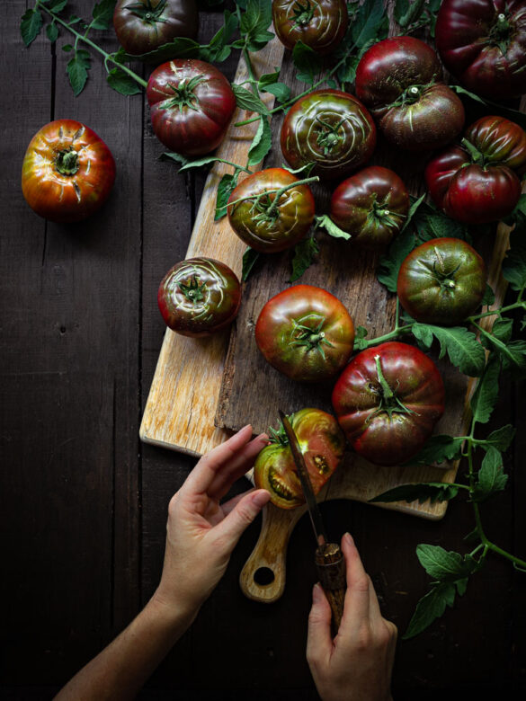Rustic scene of Black Russian tomatoes being chopped on a wooden chopping board
