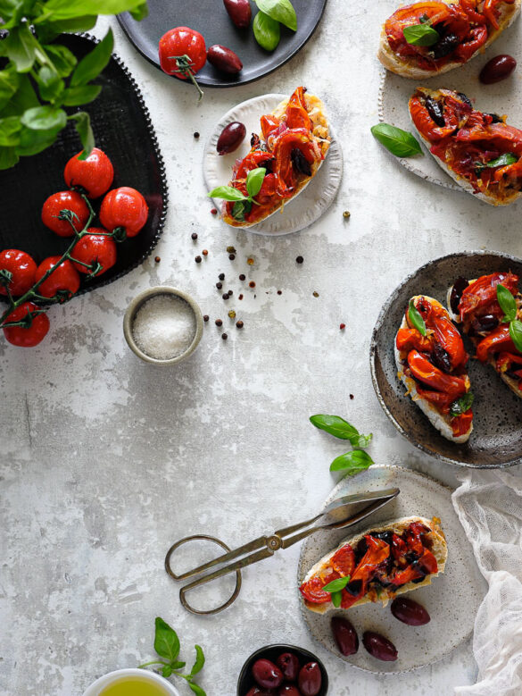 Overhead shot of little plates with bruschetta with fresh basil and cherry tomatoes in the scene