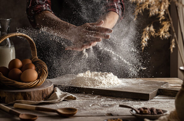 A baking scene with two hands clapping flour that is flying everywhere
