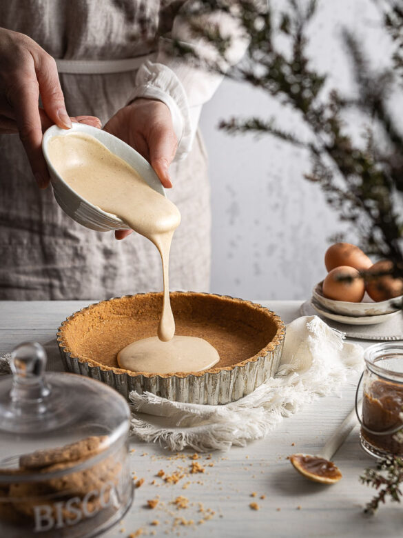 A baker pouring gingerbread cheesecake batter onto the base, a big blob frozen in time