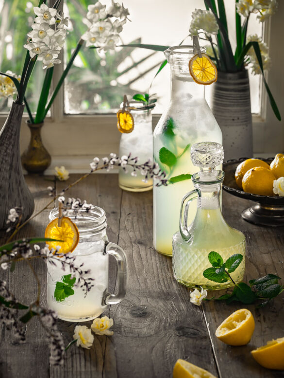 A scene by a window with homemade lemonade in a jug and classes, decorated with lemon slices