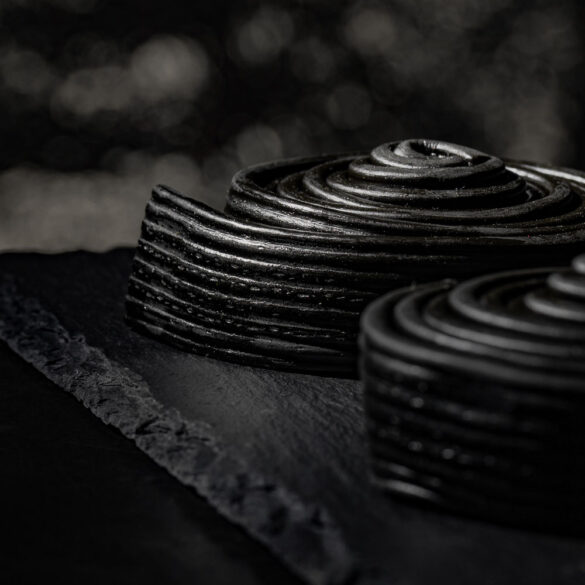 Close up of two liquorice snails on a slate board with bokeh in the background