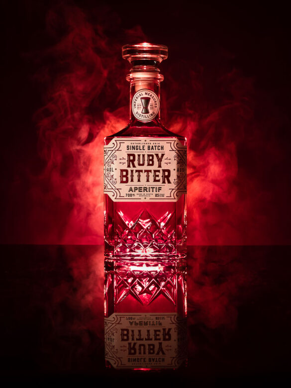 A bottle of Ruby Bitter in front of a steaming red background