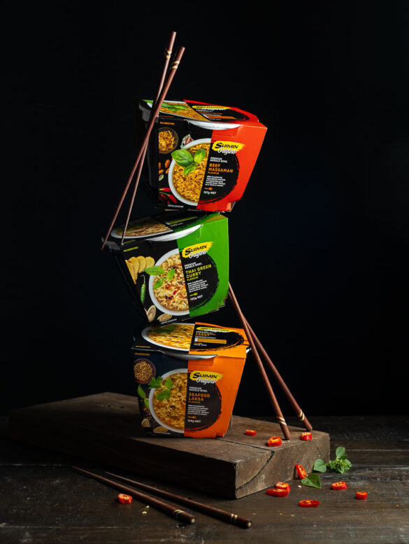 Three Suimin noodle boxes balancing on top of each other with chopsticks leaning against them