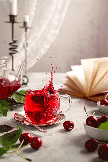 Glass cup with splashing red drink, frozen in time, with pages of book fluttering in the wind in the background