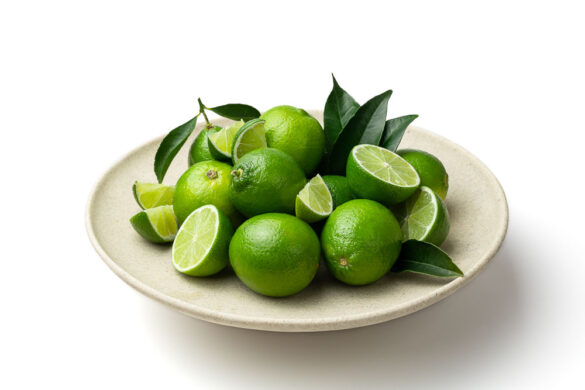 Group of cut and uncut lime on a plate with leaves